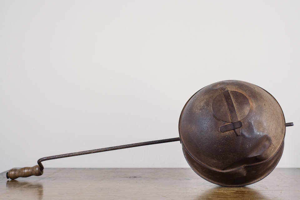 Esfera de metal interligada à uma haste em metal com a extremidade em madeira