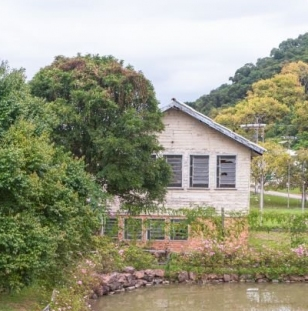 casa de tijolos com árvores e um lago ao seu redor