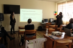 professoras sentadas em uma sala de aula assistindo a uma apresentação no datashow