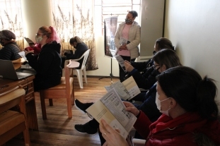 professoras sentadas nas cadeiras em uma sala de aula, acompanhando a leitura em livros